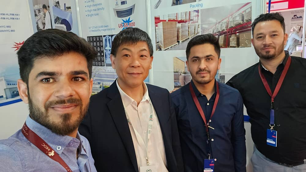 Team members at an exhibition with medical imaging and logistics information panels.
